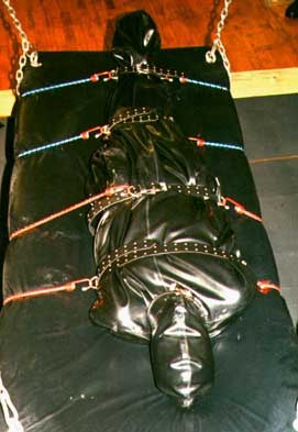 Sharina Nicole's latex fetishist Rubber kitty is strapped down in a latex bondage bag with bungee cords to the suspension swing at the Dungeon of Wrapture